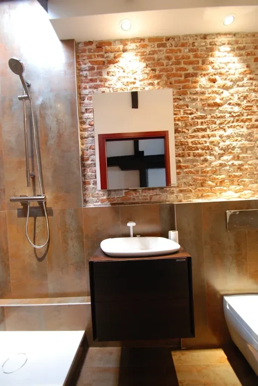 Baño reformado con pared de ladrillo visto, ducha y lavabo sobre mueble suspendido